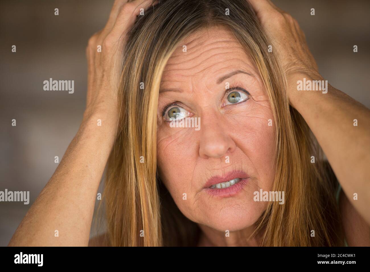 Portrait Attraktive reife Frau, gestresst, ängstlich, ängstlich, unglücklicher Ausdruck, Hände bedeckend Kopf, nach oben schauen, verschwommener Hintergrund. Stockfoto