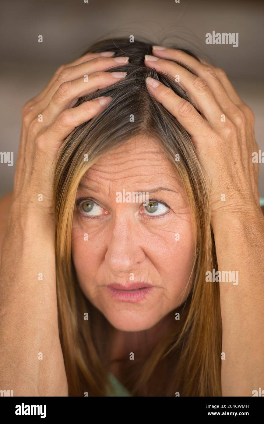 Portrait Attraktive reife Frau, gestresst, verängstigt, unglücklich erschreckt Blick, Hände über Kopf, verschwommener Hintergrund. Stockfoto