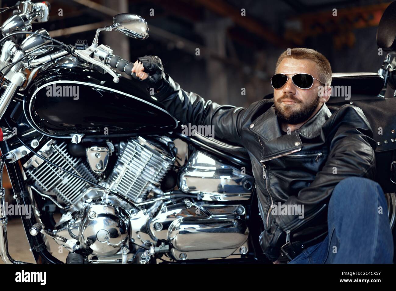 Cooler Mann Biker in Sonnenbrille sitzt neben seinem Motorrad  Stockfotografie - Alamy