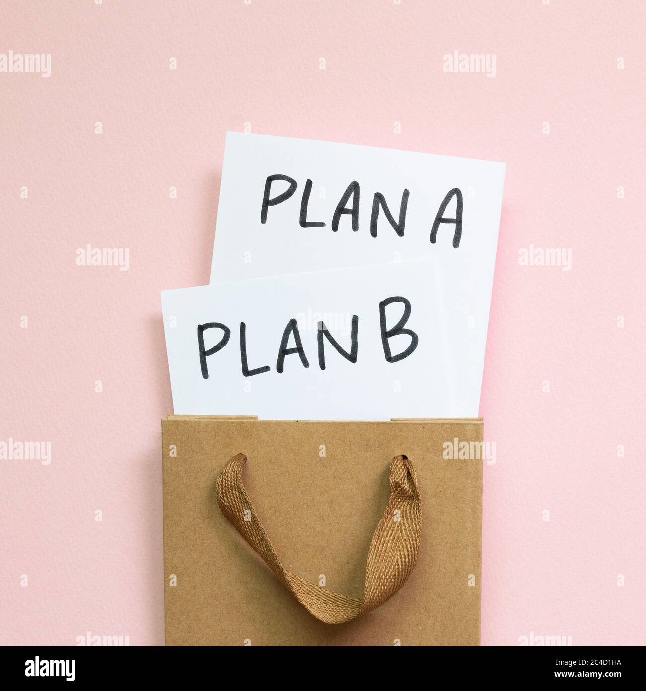 Plan A und Plan B in einem Kraftpapier-Beutel auf rosa Hintergrund. Businessplan, Wahl, Veränderung, Dilemma-Konzept. Draufsicht Stockfoto