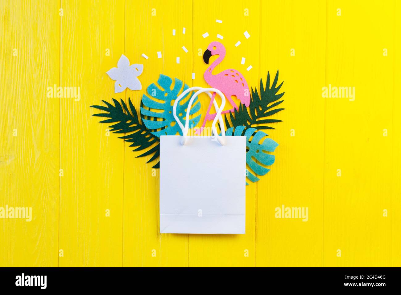 Mockup Sommer tropische Lückenlosigkeit mit Flamingo Vogel auf gelbem Holzhintergrund. Dschungelpalme und Monstera Blätter mit Paket Copyspace für Begrüßung Stockfoto