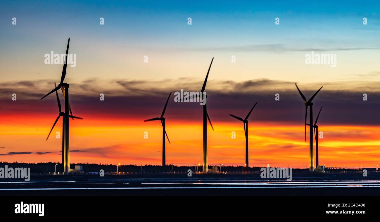 Windturbinen oder Windenergiewandler in der Sonnenuntergangszeit mit rosigen Wolken im Hintergrund Stockfoto