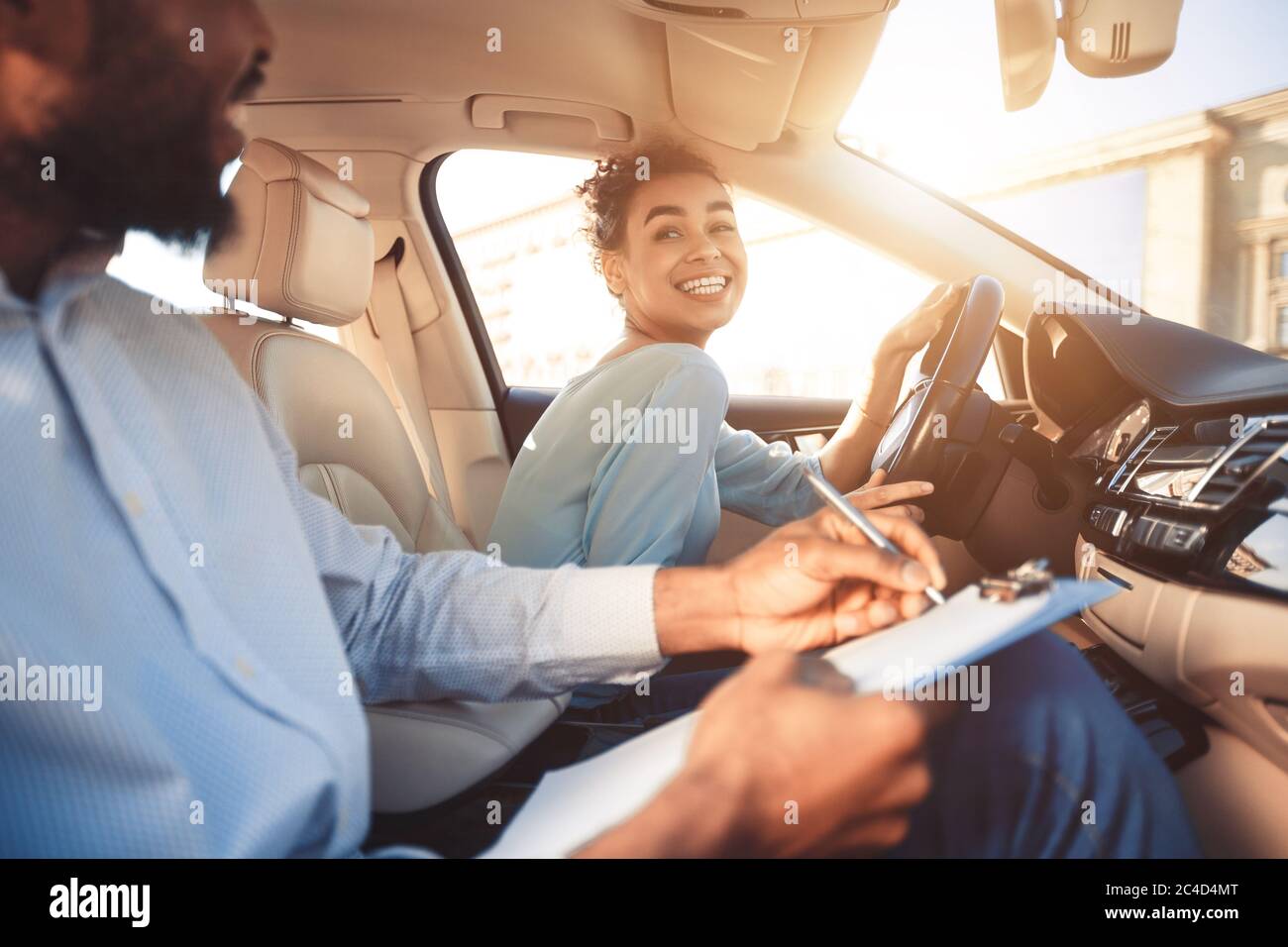 Frau, Die Auto Fährt, Sitzt Mit Instruktor Während Der Probefahrt, Abgeschnitten Stockfoto