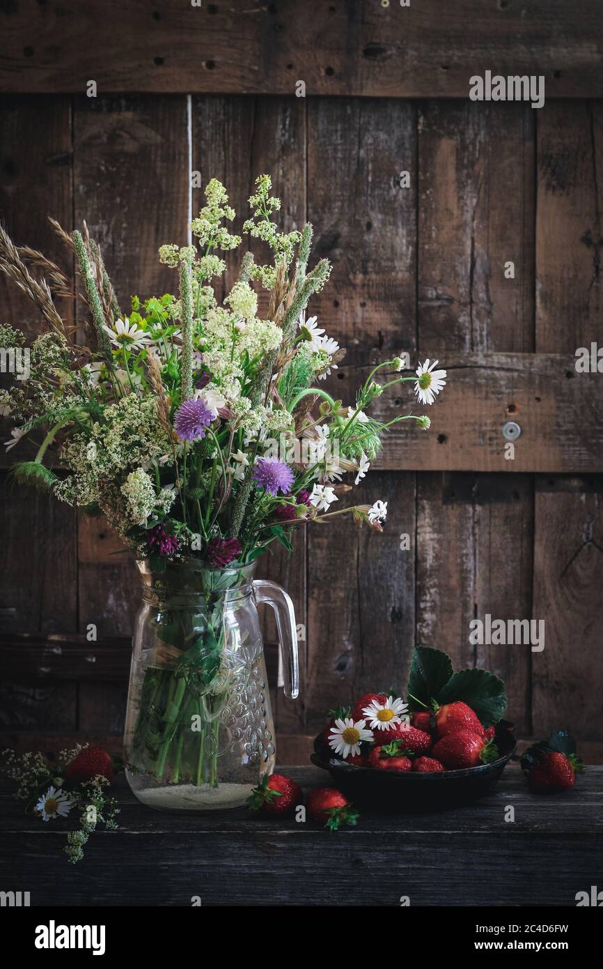 Ländliche Umgebung mit wilden Blumen und Erdbeeren Stockfoto