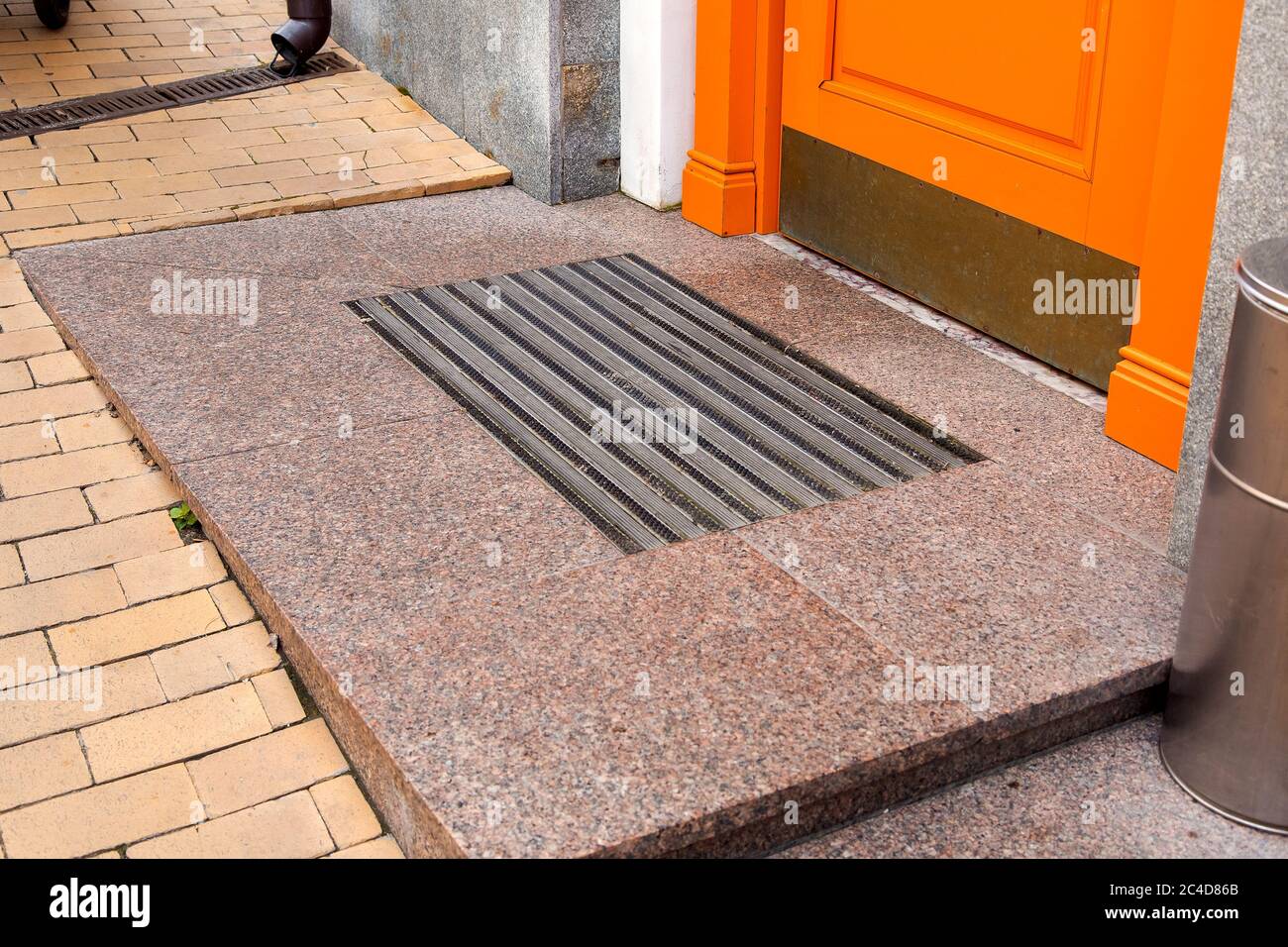 Schwelle einer orangefarbenen hölzernen Eingangstür mit Fußmatte Nahaufnahme Seitenansicht. Stockfoto