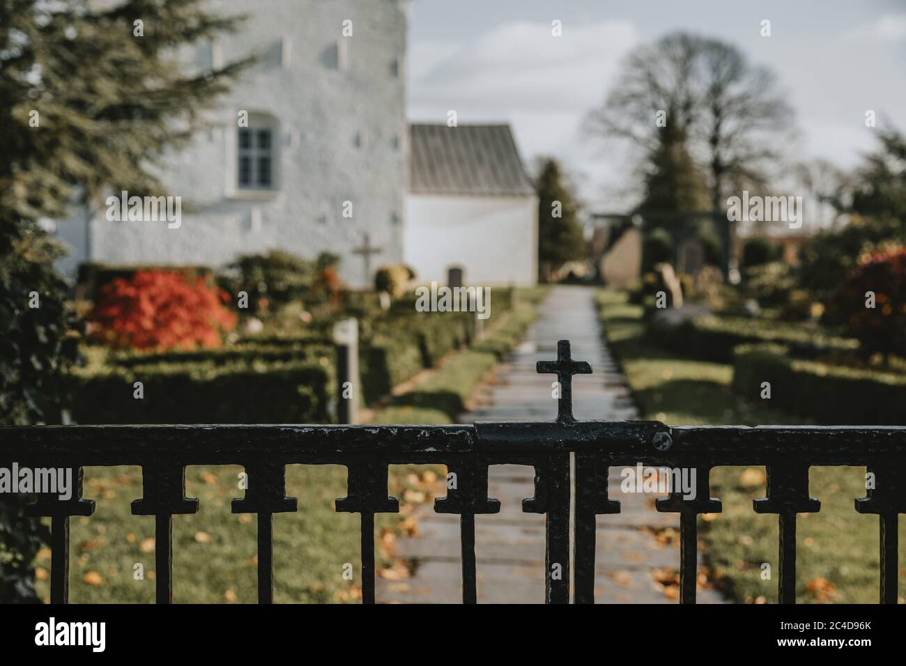 Das Detail des christlichen Kreuzes auf dem oberen Teil des Eingangstors zum Jelling Friedhof in Dänemark mit den ältesten wikingerrunen Steinen während des Herbsttages Stockfoto