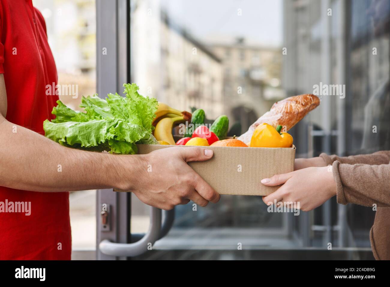 Lieferung aus dem Supermarkt. Kurier übergibt Karton mit Lebensmitteln Stockfoto