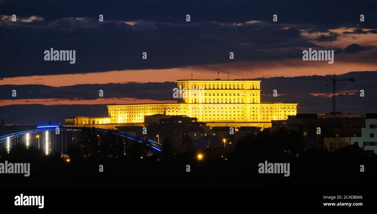 Der Palast des Parlaments (Palatul Parlamentului auf Rumänisch) in Bukarest, Rumänien, beleuchtet in der Nacht, zwischen dunklen Wolken. Skyline von Bukarest, To Stockfoto