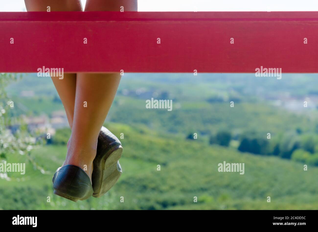 Die Beine der Frau von einer Bank mit grüner Naturlandschaft im Diskance Stockfoto