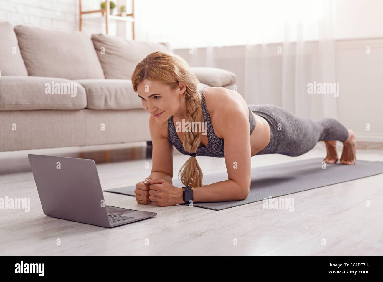 Sportliche Aktivitäten zu Hause allein. Frau sieht Fitness-Unterricht auf Laptop Stockfoto