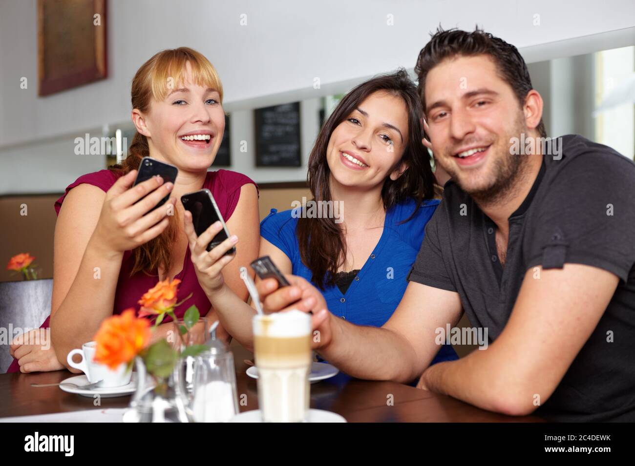 Lachgruppe mit ihren Handys im Café Stockfoto