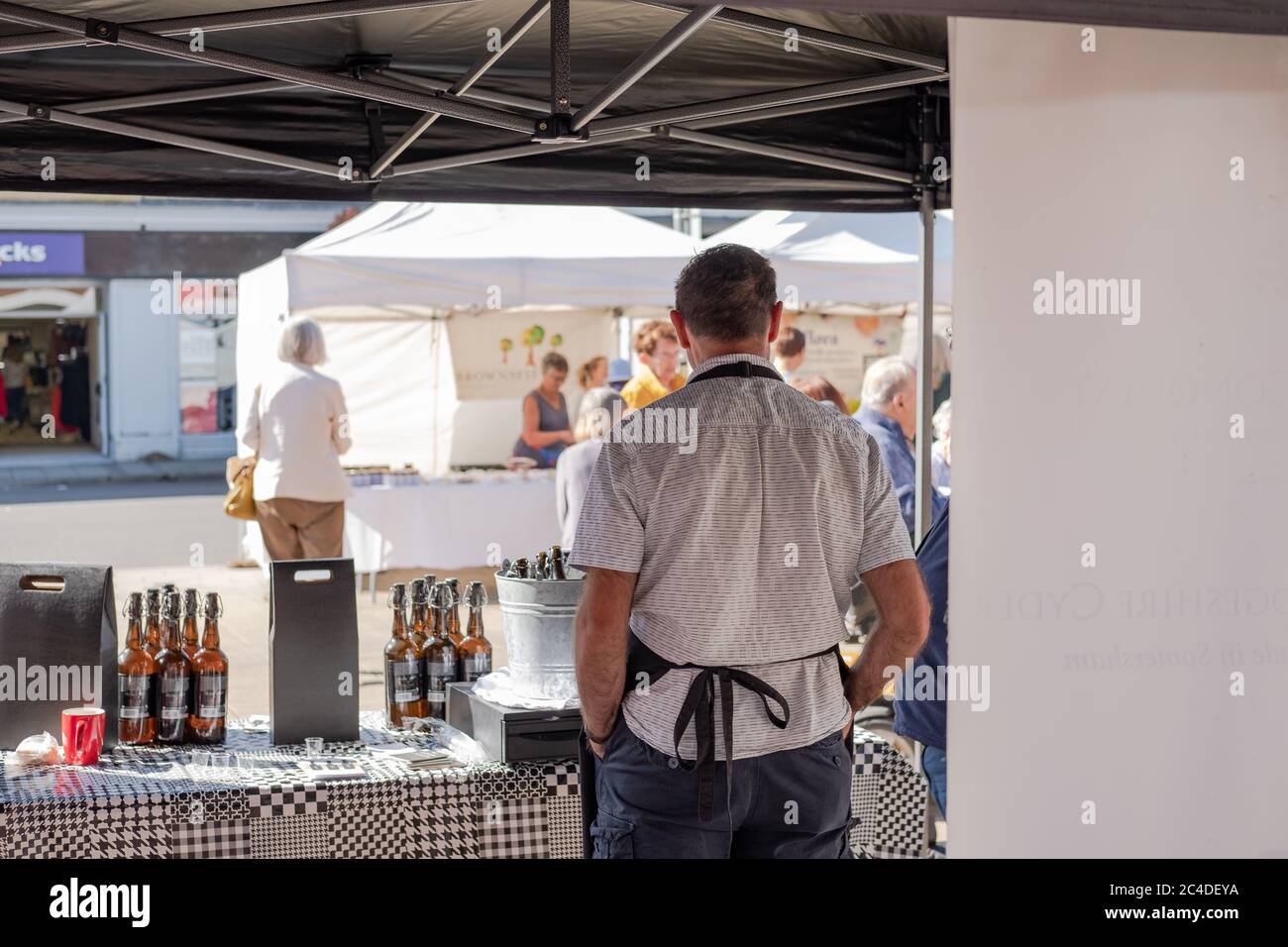 Der Kreditmarkt-Trader, der hinter sich steht, ist am Stall. Auf dem Tisch sind verschiedene abgefüllte Produkte zu sehen. Stockfoto