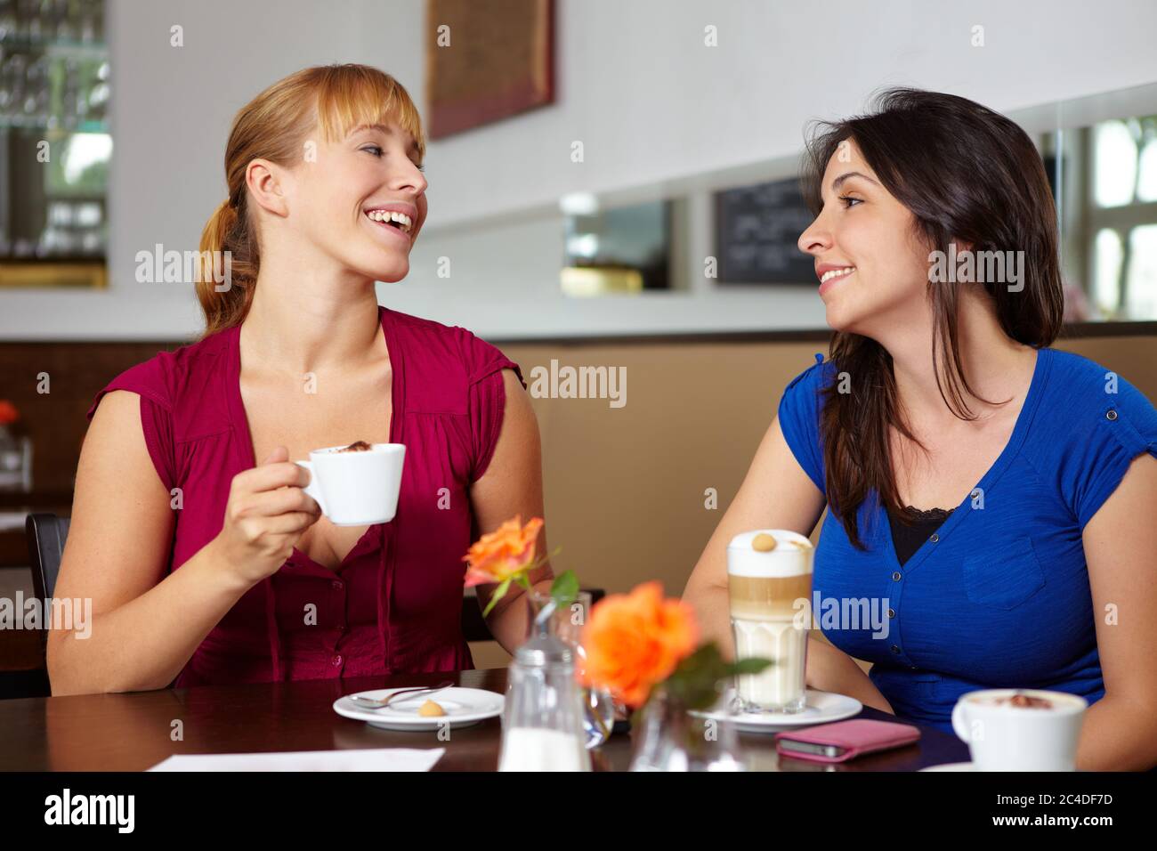 Zwei lachende Frauen mit Kaffee im Café Stockfoto