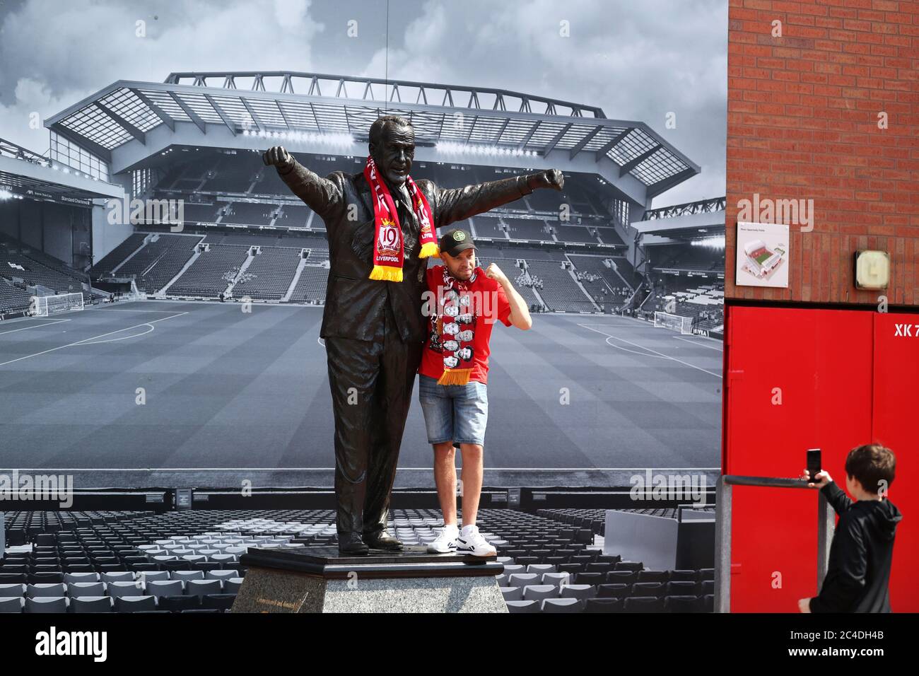 Liverpool-Fan Anthony Furns posiert für ein Foto mit der Bill Shankly Statue vor Anfield in Liverpool. Stockfoto