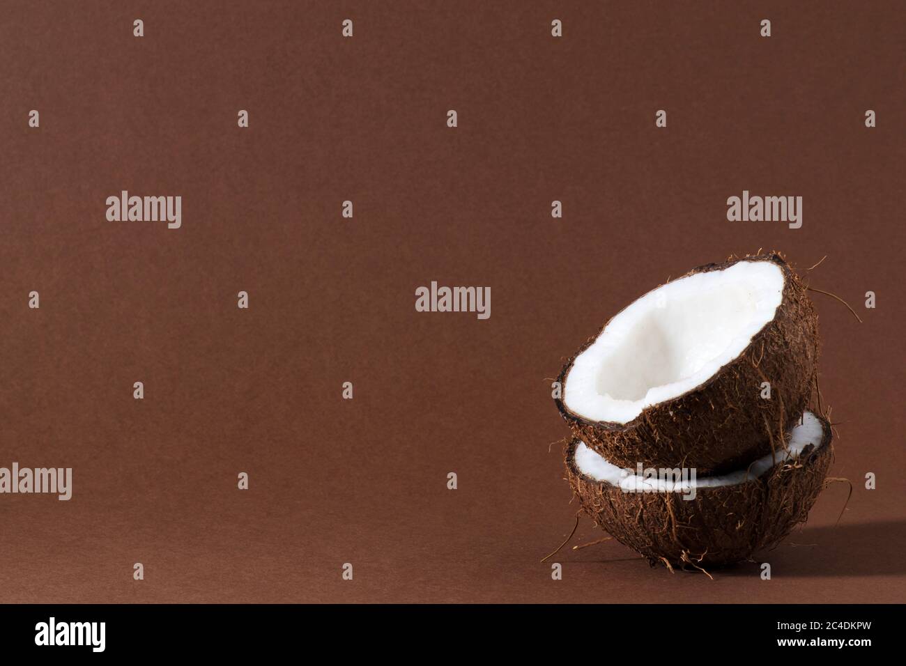Reife halbgeschnittene Kokosnuss auf braunem Hintergrund. Stockfoto