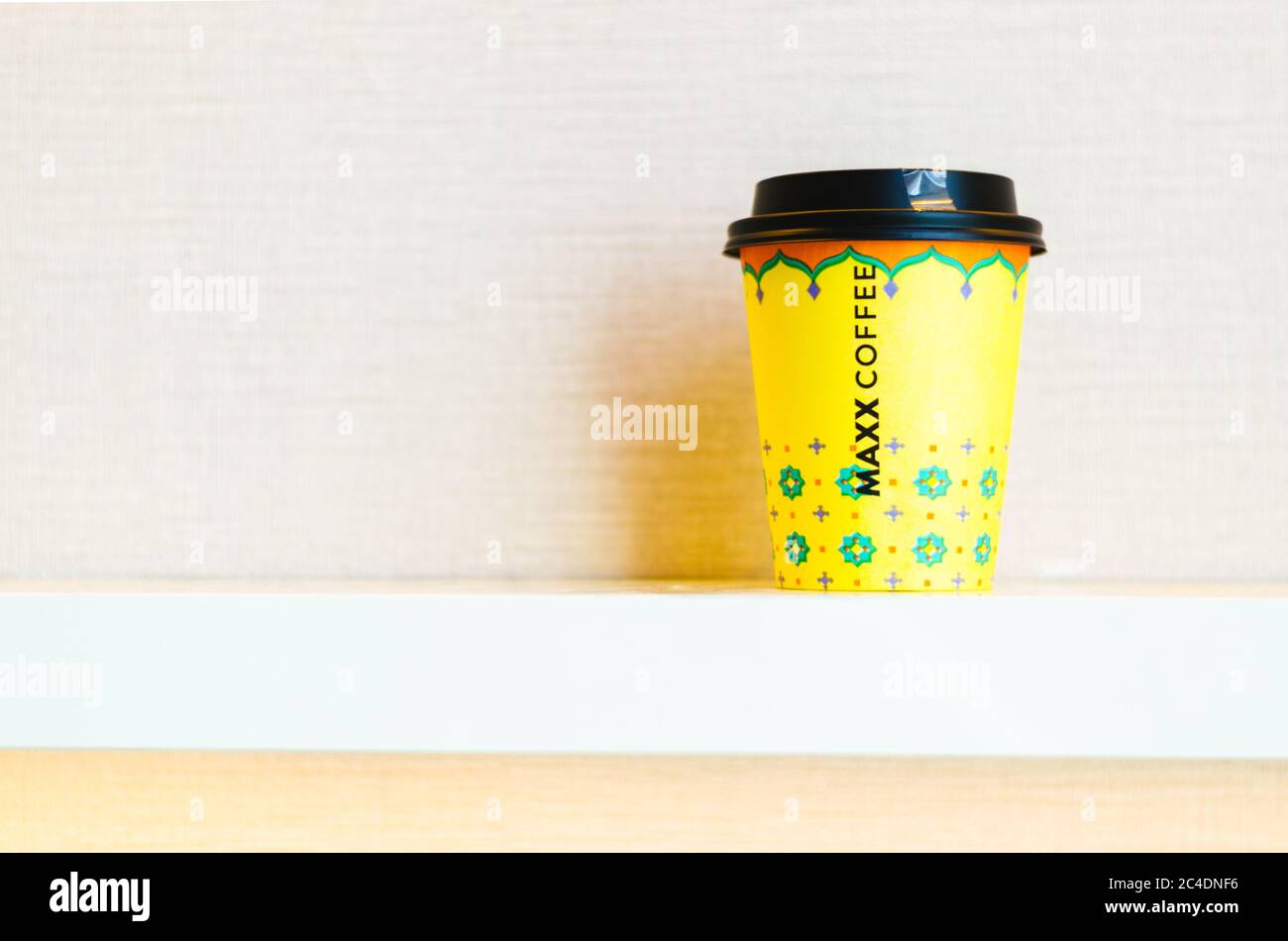 Eine gelbe Take Away Tasse Kaffee mit dem Namen der Maxx Coffee Kette in der Mitte der Tasse. Stockfoto