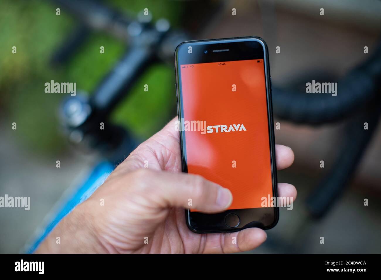 Eine Hand mit einem i-Phone zeigt Strava Fahrrad und Lauf App mit Fahrrad.  Foto von Sam Mellish Stockfotografie - Alamy