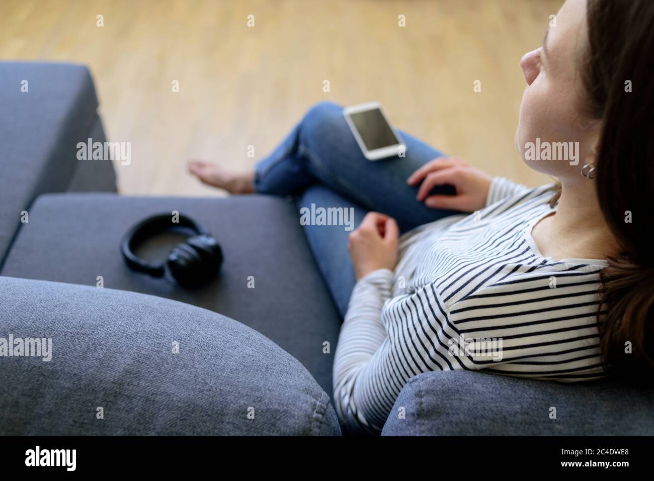 Frau sitzt mit Handy auf der Couch. Müde. Digitales Detox-Konzept Stockfoto