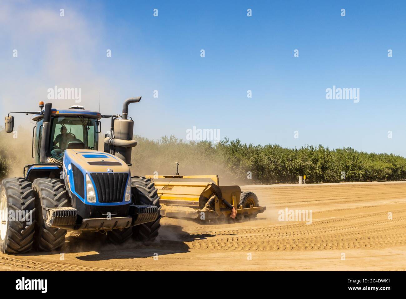 Ein Traktor aus New Holland nivellieren ein Feld in der Nähe von Modesto California USA, um die Leistung der Hochwasserbewässerung zu verbessern Stockfoto