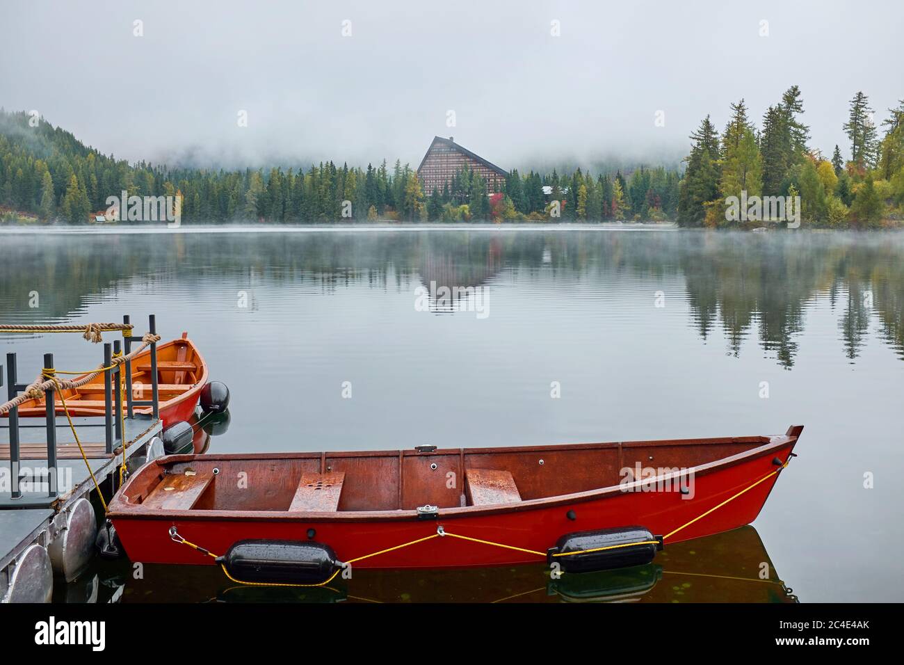 Nebliger Herbst Strbske See mit Rückbau und roten Booten im Vordergrund auf dem Wasser im Nationalpark hohe Tatra, Slowakei Stockfoto
