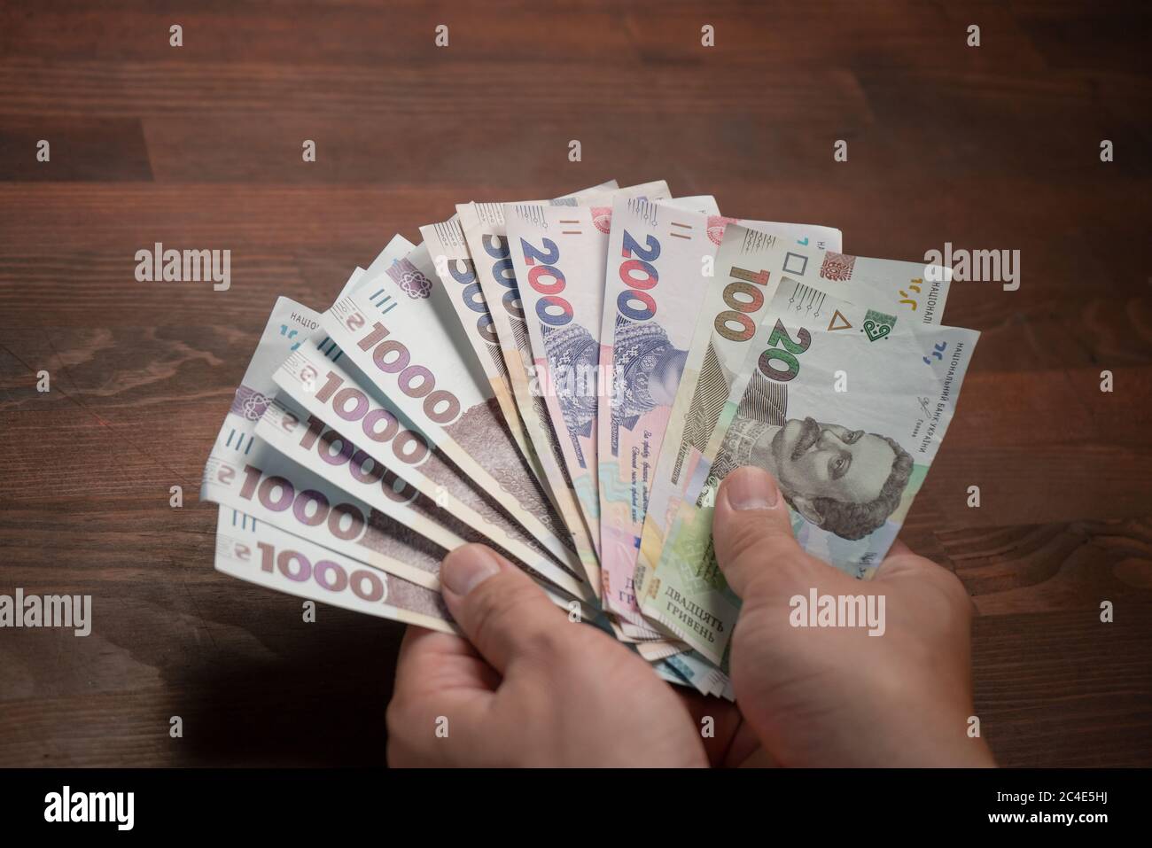 Kaukasischer Mann mit ukrainischer Papierbanknote, Griwnien. Männliche Hände und Pack neues Geld. Exchange-Konzept. Weitwinkelansicht Stockfoto