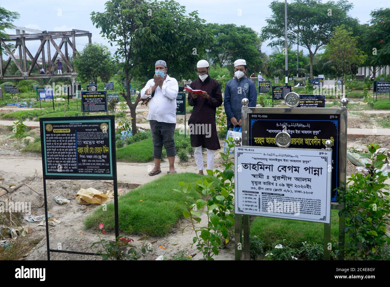 Angehörige mit Gesichtsmasken beten als vorbeugende Maßnahme vor dem Grab eines Coronavirus-Opfers.Bangladesch hat insgesamt 130,474 bestätigte Fälle registriert, von denen 53,133 geborgen und 1661 an den Folgen des Coronavirus gestorben sind. Stockfoto