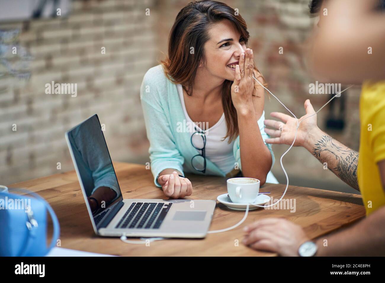 Junge kaukasische Frau, die mit der Hand über dem Mund lachend und dem männlichen Partner zuhört Stockfoto