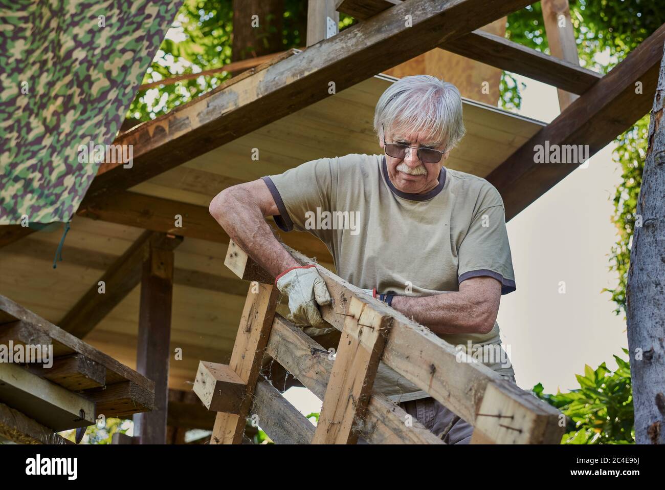 Aktiver älterer Mann im Ruhestand, der auf dem Hinterhof arbeitet, lächelnd Stockfoto