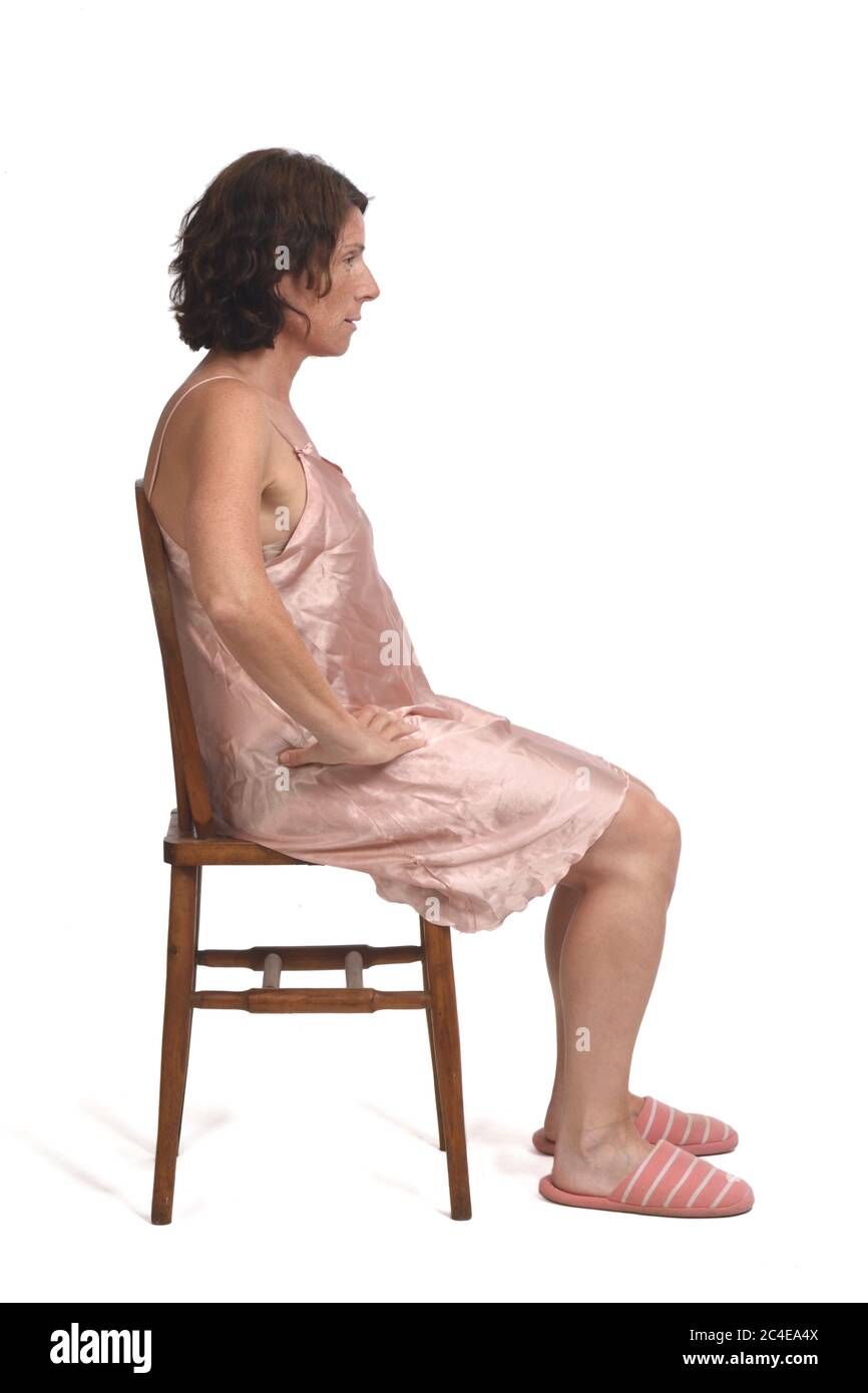 Seitenansicht einer Frau mit Nachthemd auf weißem Hintergrund sitzen, Seitenansicht Seite aussehen, ernst Stockfoto
