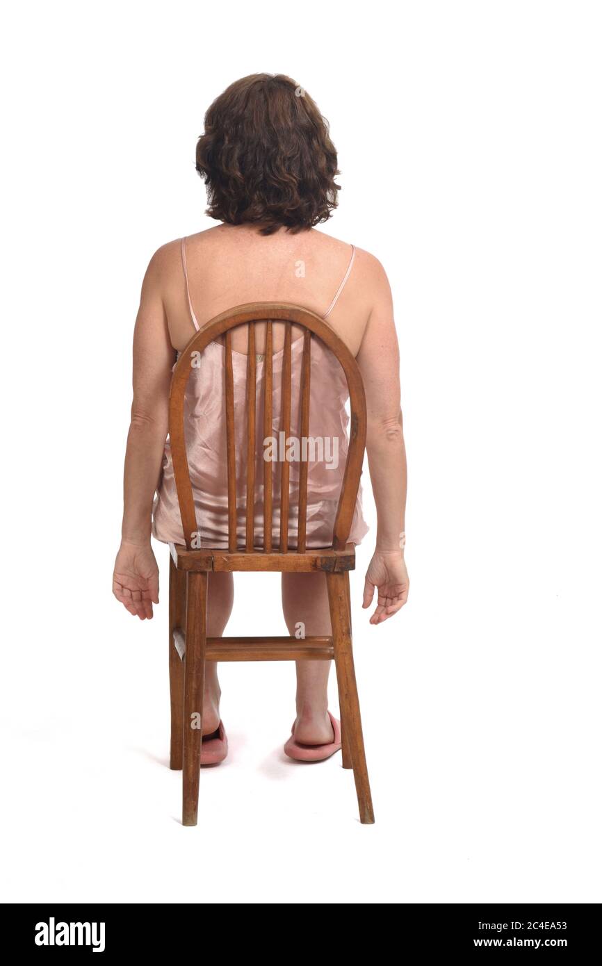 Rückansicht einer Frau mit Nachthemd auf weißem Hintergrund sitzend, Stockfoto