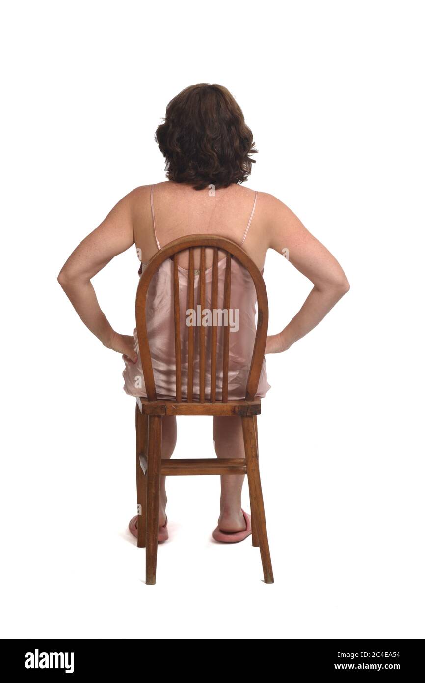 Rückansicht einer Frau mit Nachthemd auf weißem Hintergrund sitzend, Stockfoto