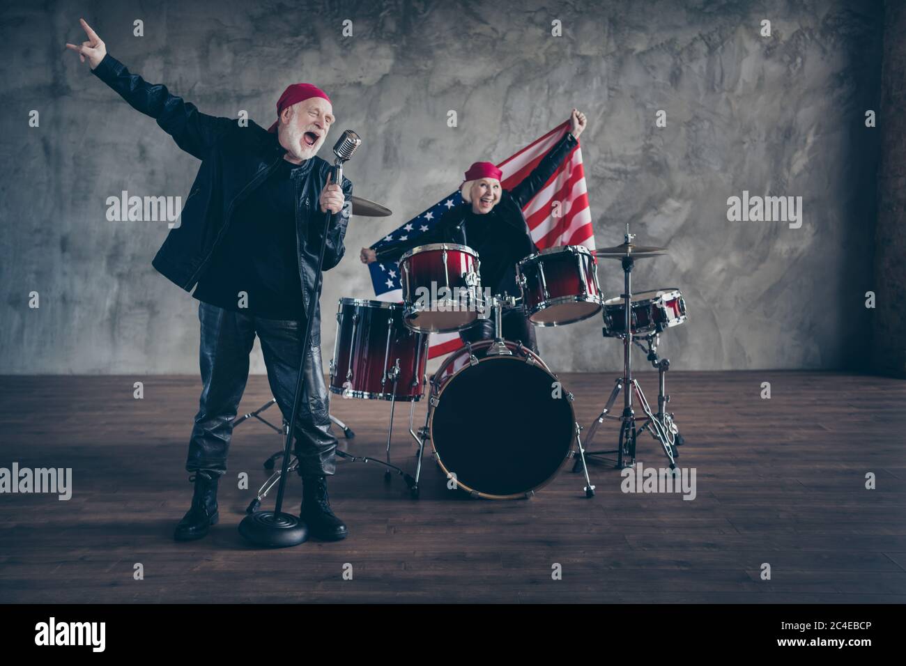 Foto von zwei Rentner Rockband Gruppe Konzert spielen Schlagzeug Instrumente singen mic Hold usa Flagge patriotische Partei tragen Rocker Leder Outfit Stockfoto