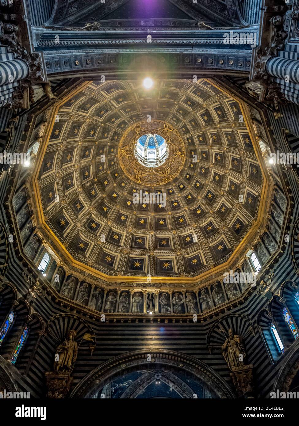 Innenkuppel mit sechseckiger Kuppel, gekrönt von Berninis goldener Sonnenlaterne. Kathedrale Von Siena. Italien. Stockfoto