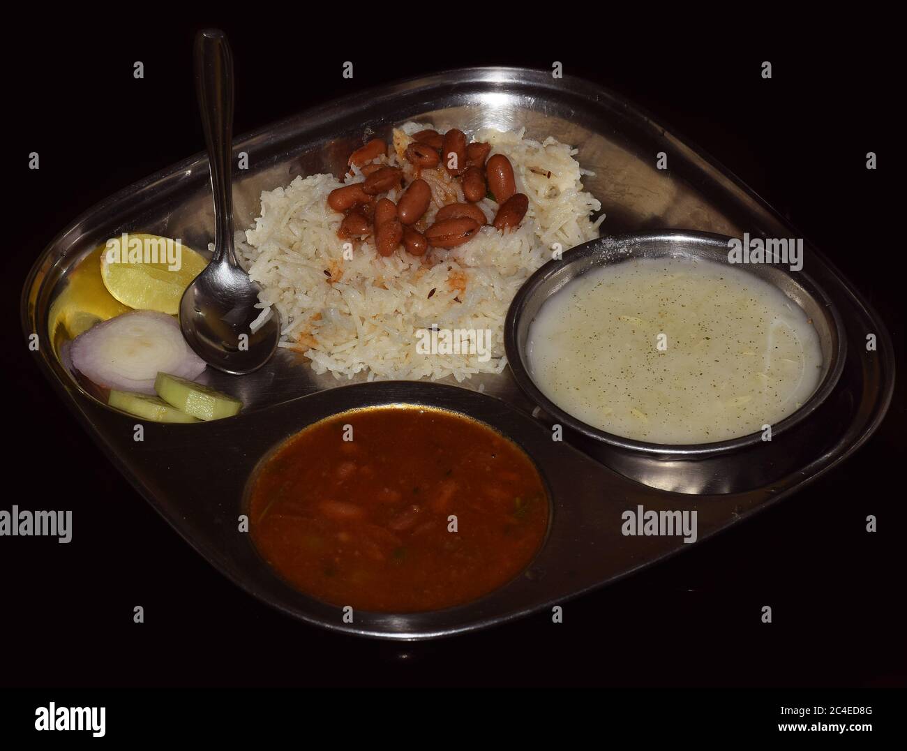 Jeera Reis mit Rajma (Nierenkerne Curry) und Raita (auf Joghurtbasis) auf einem Stahlteller serviert. Stockfoto