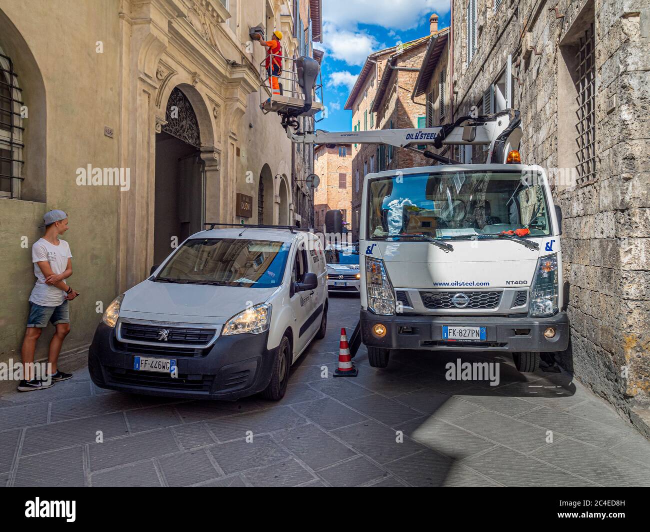 Arbeiter auf LKW montiert Kirsche Picker in einer engen Straße in Siena, Italien. Stockfoto