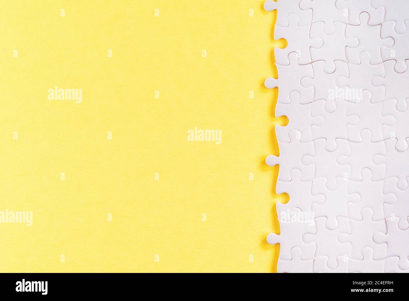 Weiße Puzzle-Stücke auf gelb. Abstrakte Vorlage und Hintergrund mit Kopierraum Stockfoto
