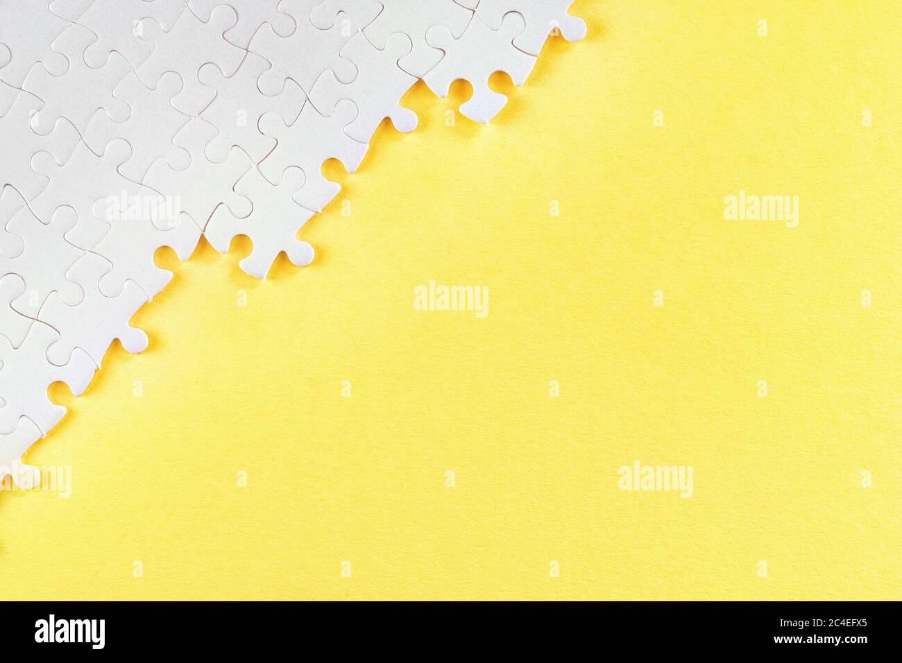 Weiße Puzzle-Stücke auf gelb. Abstrakter Hintergrund mit Kopierbereich Stockfoto