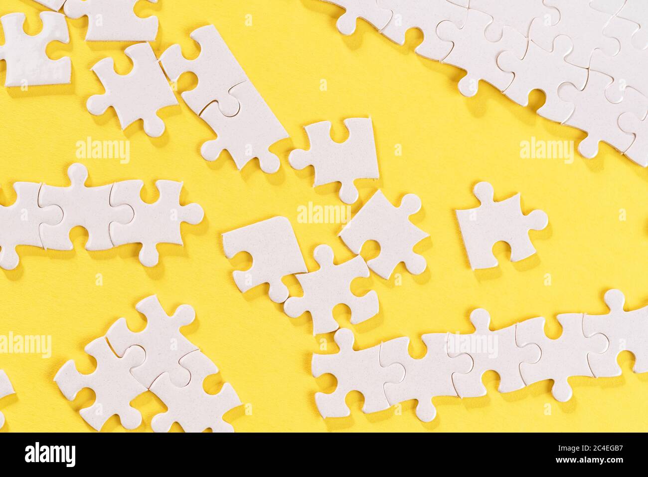 Zerlegtes weißes Puzzle-Stücke auf gelbem Hintergrund. Stockfoto