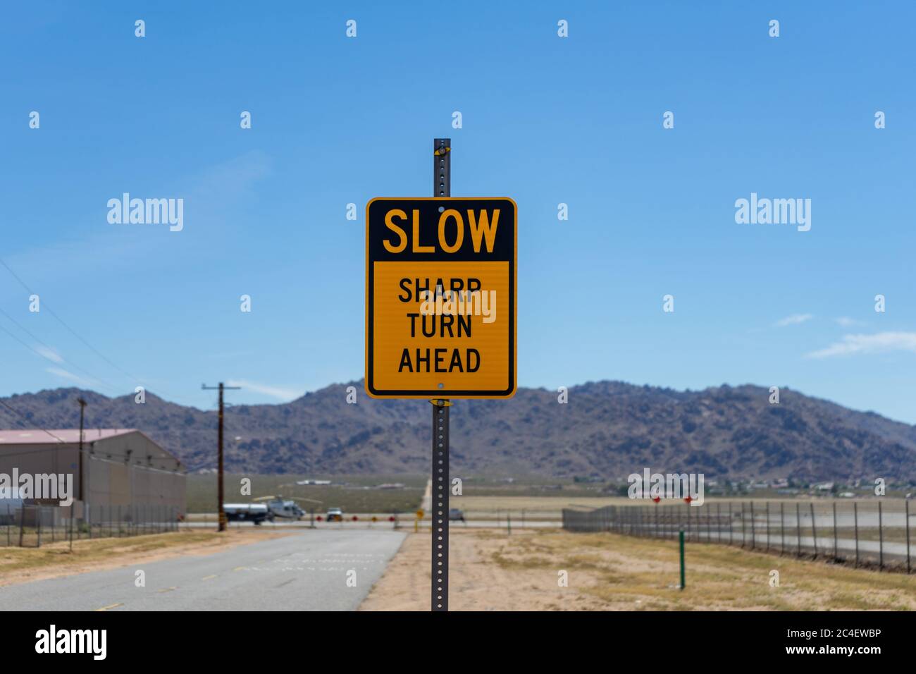 Apple Valley, CA / USA – 16. Mai 2020: Ein gelb-schwarzes Straßenschild die liest langsam Sharp Turn ahead befindet sich in Apple Valley, Kalifornien. Stockfoto