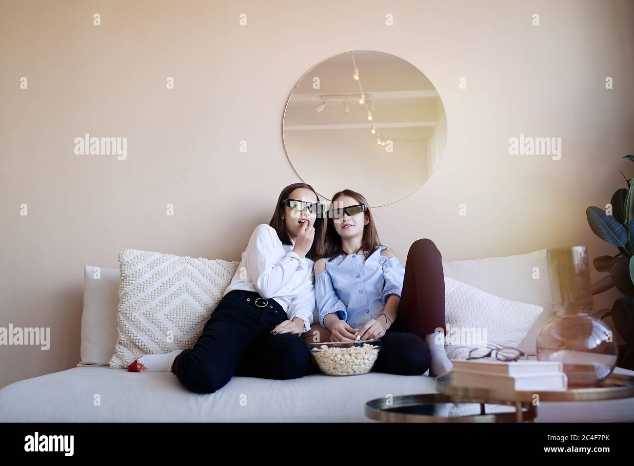 Erschrockene Freunde oder Teenager-Mädchen mit 3D-Brille essen Popcorn und Film zu Hause Stockfoto