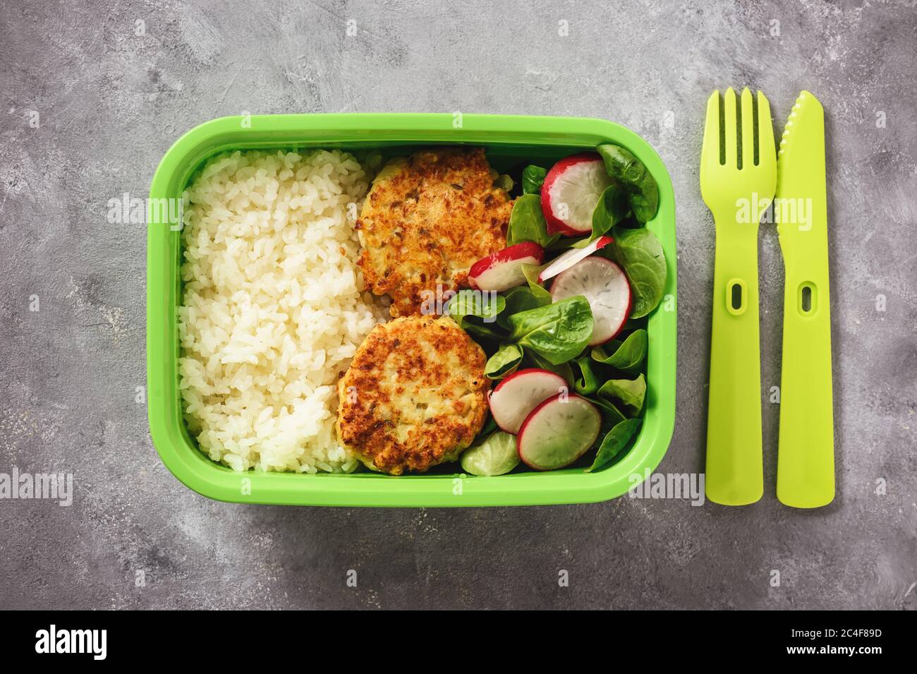 Lunchbox mit gekochtem Reis, Hühnchen-Koteletts und Radush-Salat. Stockfoto