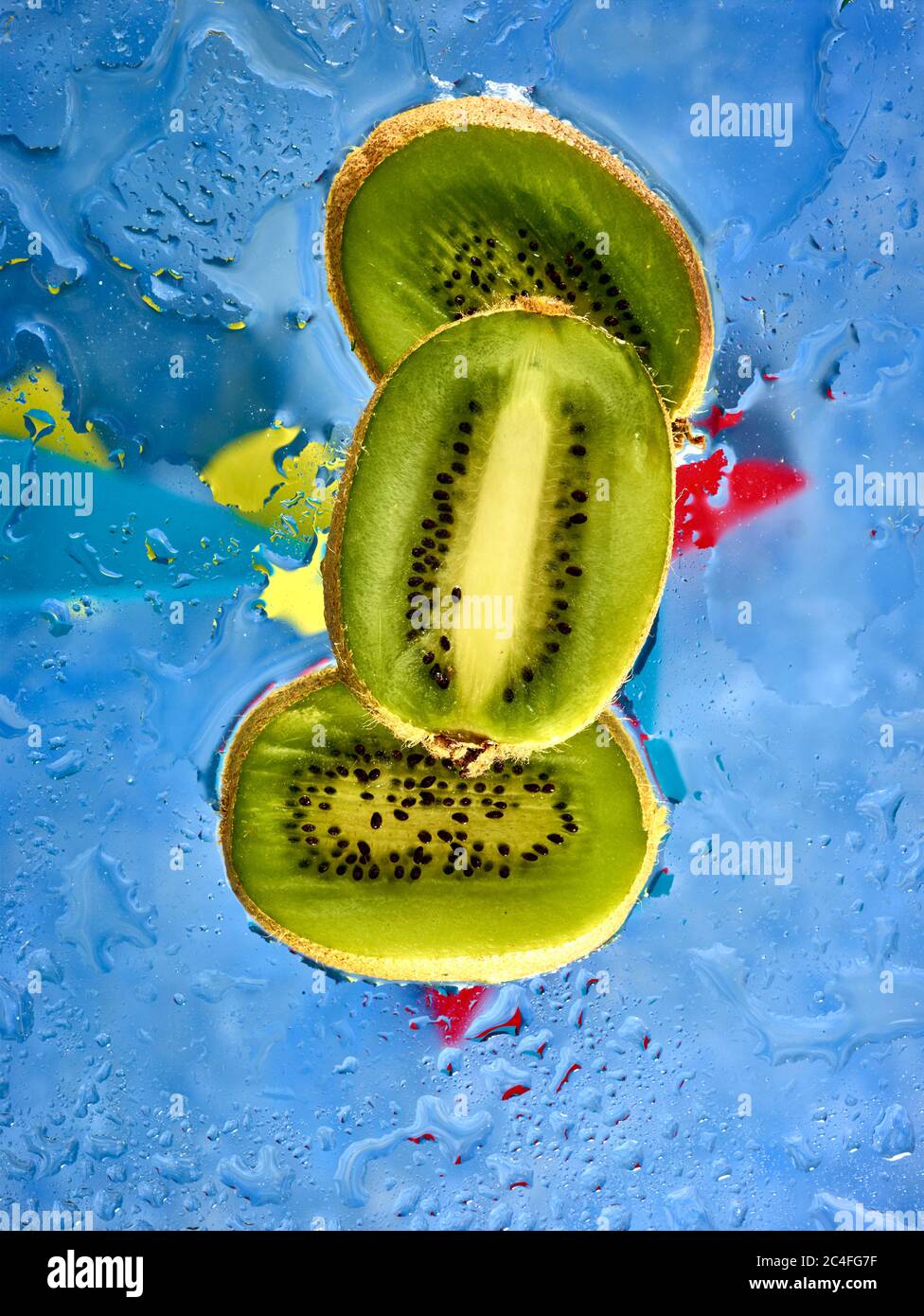 Kiwifruit Scheiben vor farbenfrohem Hintergrund und Wassertröpfchen, Farbe und Lebensmittel Stillleben Stockfoto