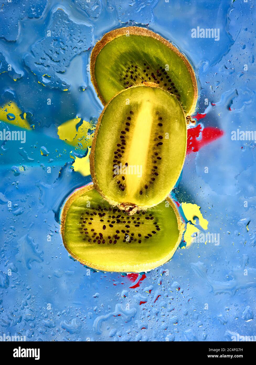 Kiwifruit Scheiben vor farbenfrohem Hintergrund und Wassertröpfchen, Farbe und Lebensmittel Stillleben Stockfoto