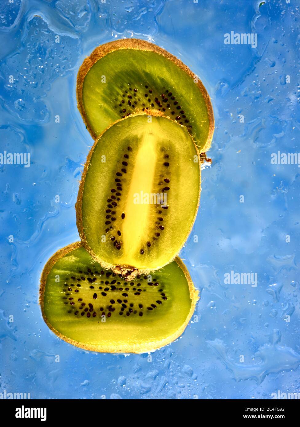 Kiwifruit Scheiben vor farbenfrohem Hintergrund und Wassertröpfchen, Farbe und Lebensmittel Stillleben Stockfoto