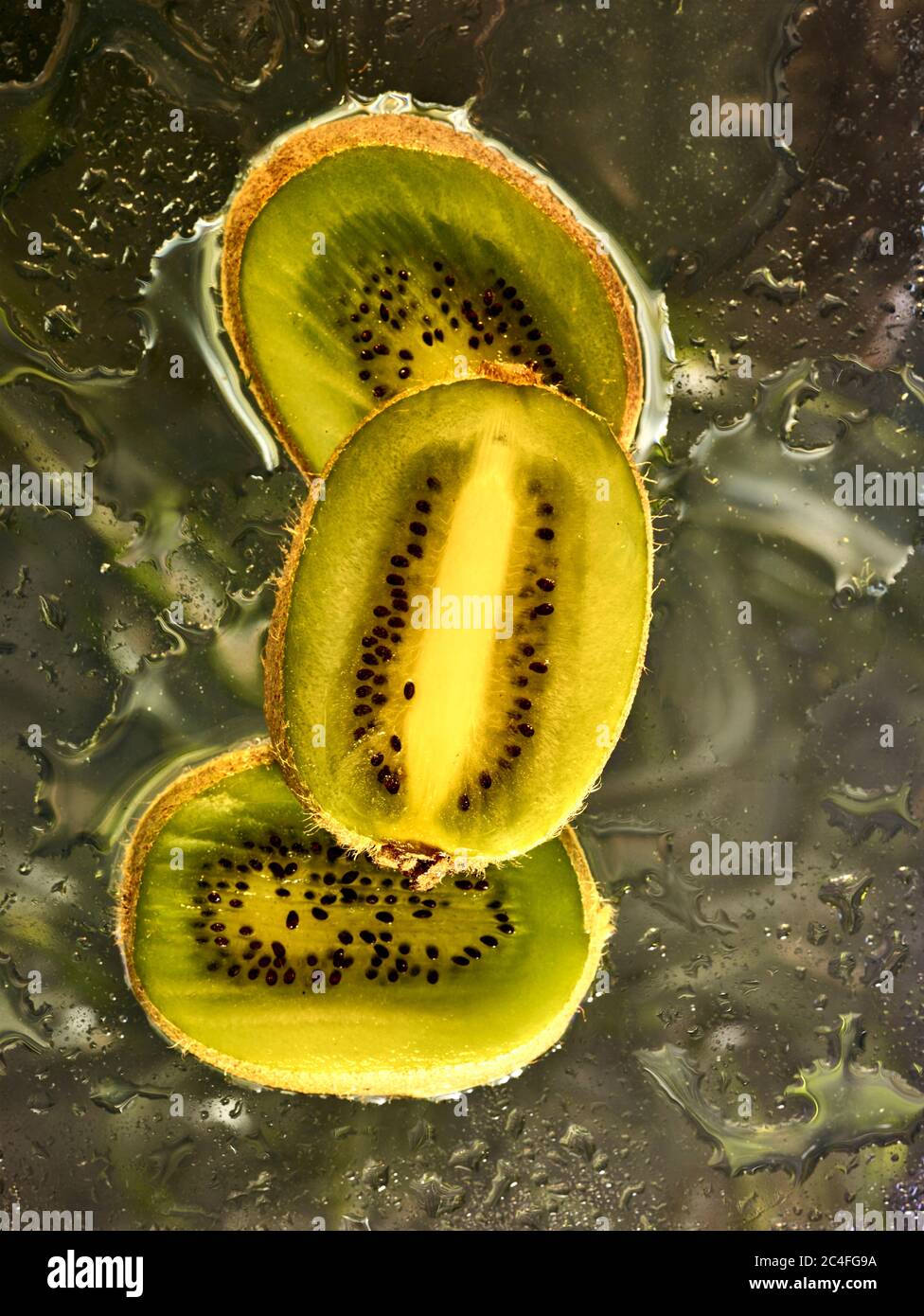 Kiwifruit Scheiben vor farbenfrohem Hintergrund und Wassertröpfchen, Farbe und Lebensmittel Stillleben Stockfoto