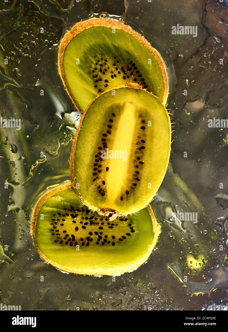 Kiwifruit Scheiben vor farbenfrohem Hintergrund und Wassertröpfchen, Farbe und Lebensmittel Stillleben Stockfoto