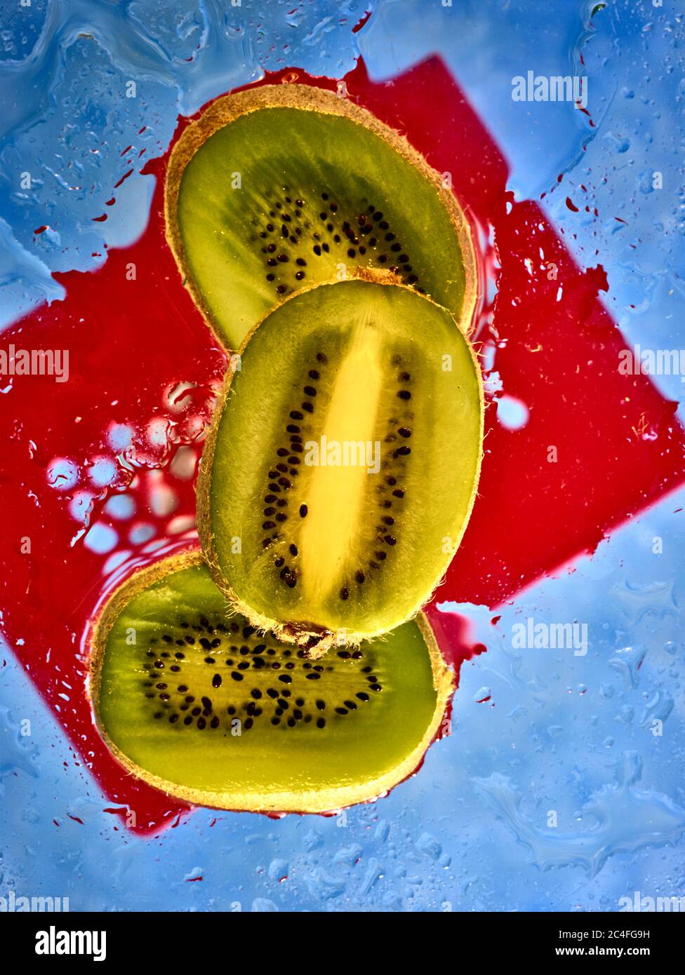 Kiwifruit Scheiben vor farbenfrohem Hintergrund und Wassertröpfchen, Farbe und Lebensmittel Stillleben Stockfoto