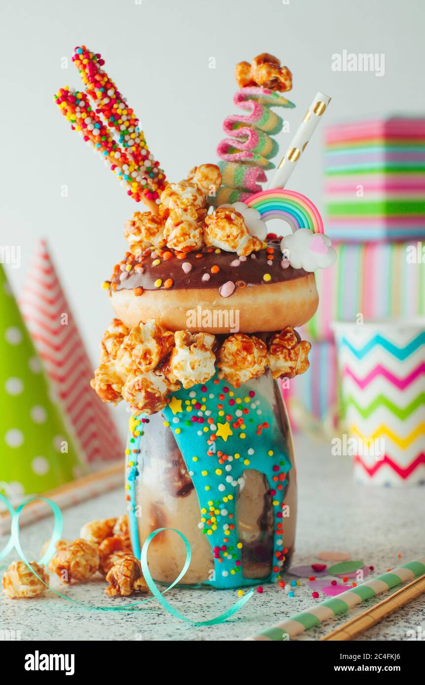 Schokofreak Shake Topping mit Donut und Karamell Popcorn auf dem Partytisch in der Nähe von Geschenk-Boxen. Selektiver Fokus. Stockfoto