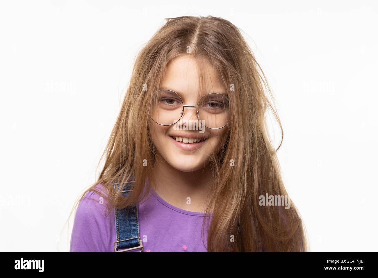 Porträt eines fröhlichen zerzausten langhaarigen Mädchen von elf Jahren in Brille Stockfoto