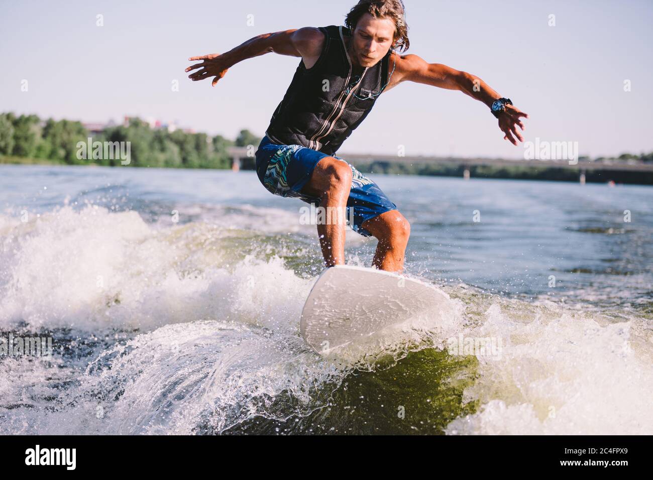 Ein Mann surft auf einem Surfbrett, das von einem Motorboot über der Welle des Bootes gezogen wird. Weixerfer beschäftigt sich mit Surfen, Unterhaltung, Freizeit, Wasser Stockfoto